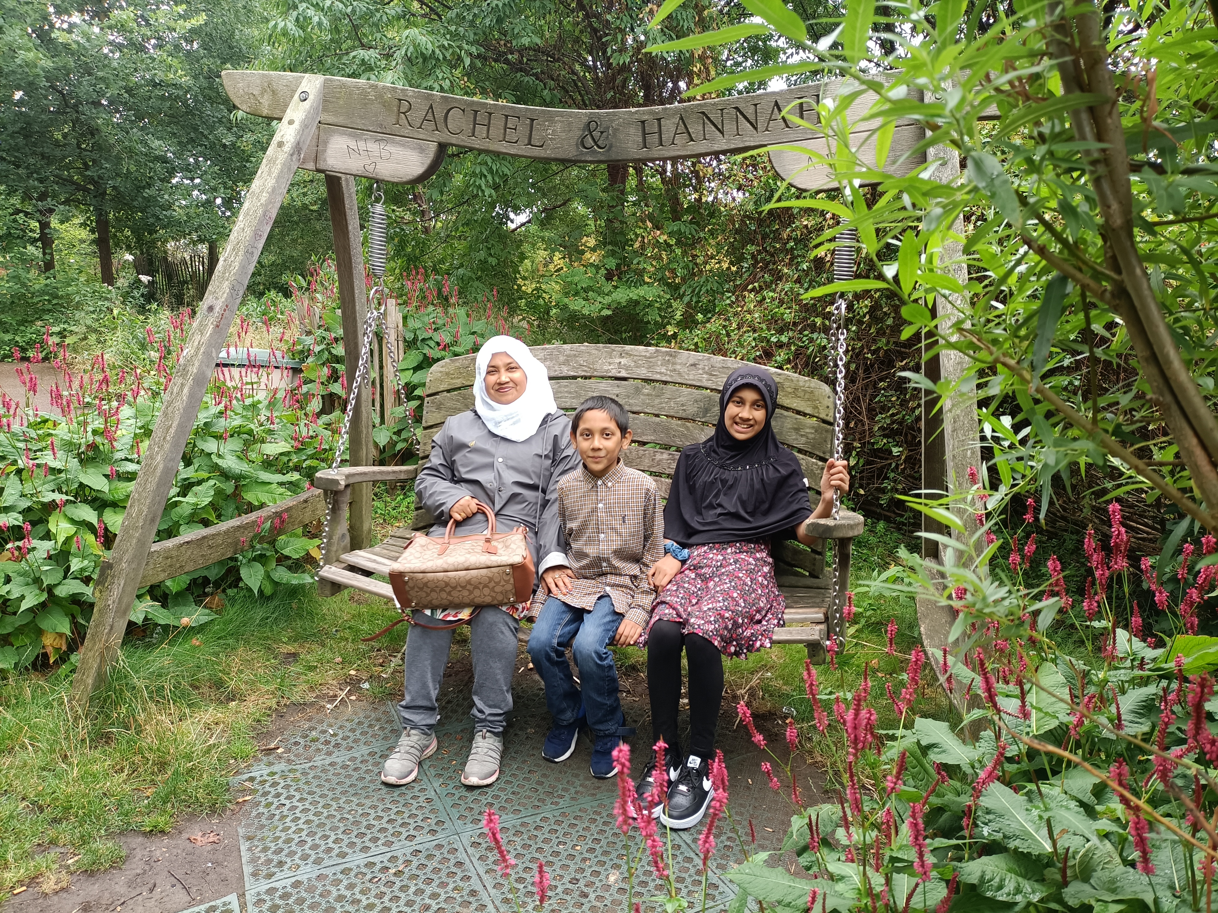 A family sit on a bench in natural urban surroundings. 