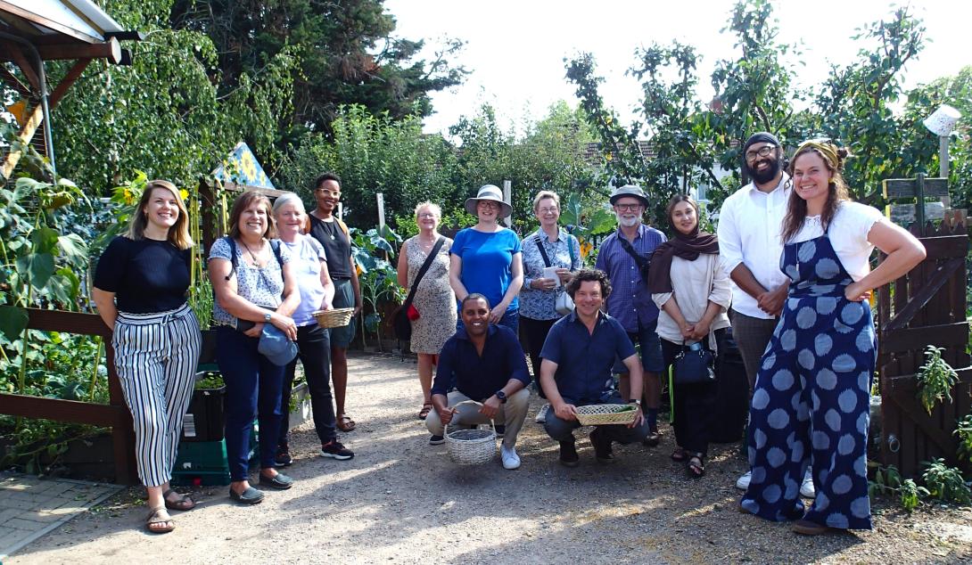 A group of people of smile at a networking tour at Sufra Community Gardens